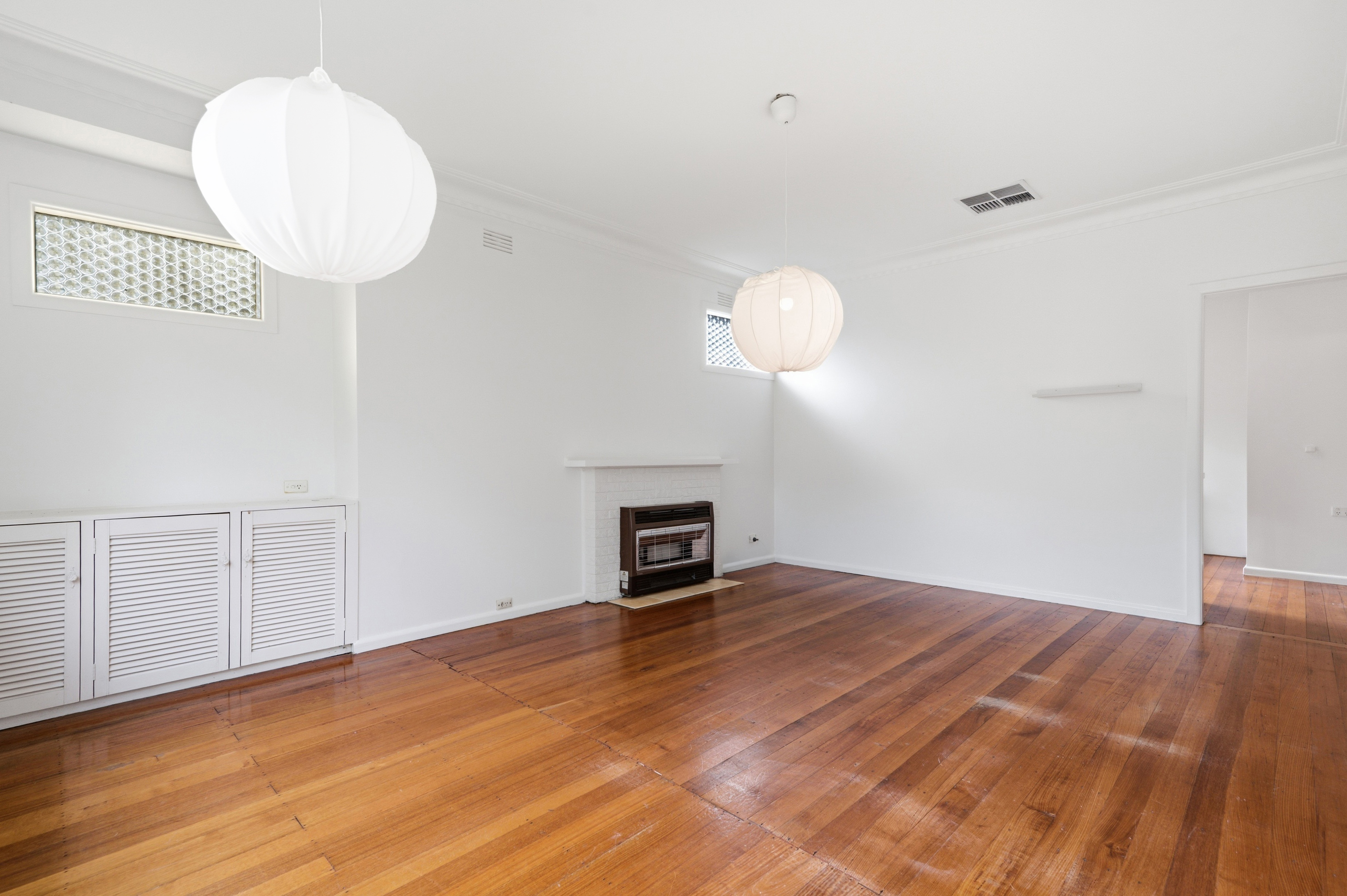 Before virtual staging: large empty open-plan zone showing hardwood floors and bare walls